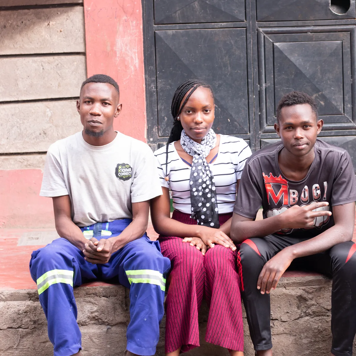 Three members of the Kichwa Connect team sitting side by side on a step, looking at the camera